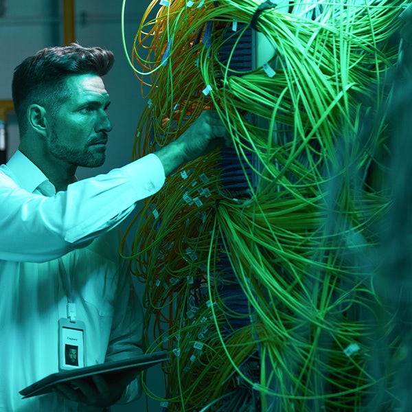 A man looking at wires in a data center.