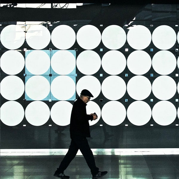 A man walking past a large wall of circles.