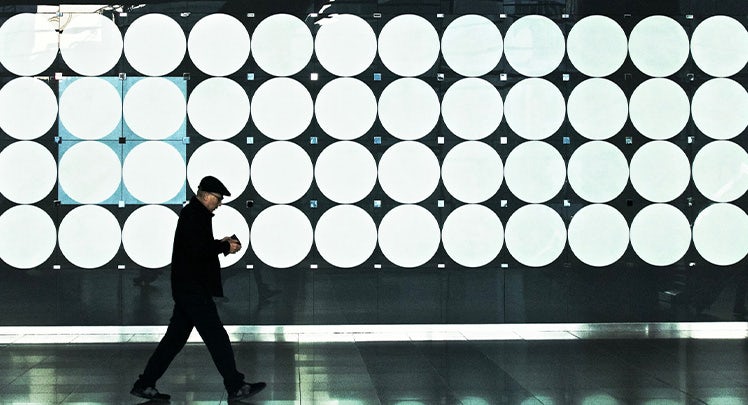 A man walks past a large circular wall display.