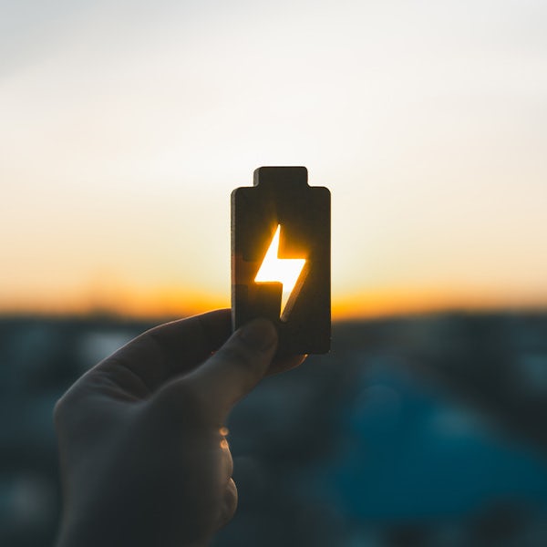 A person holding up a battery with a lightning bolt on it.