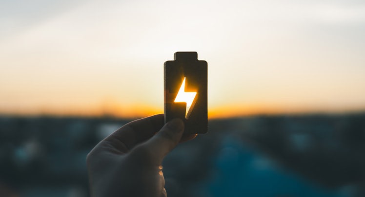 A person holding up a flashlight with a lightning bolt on it.