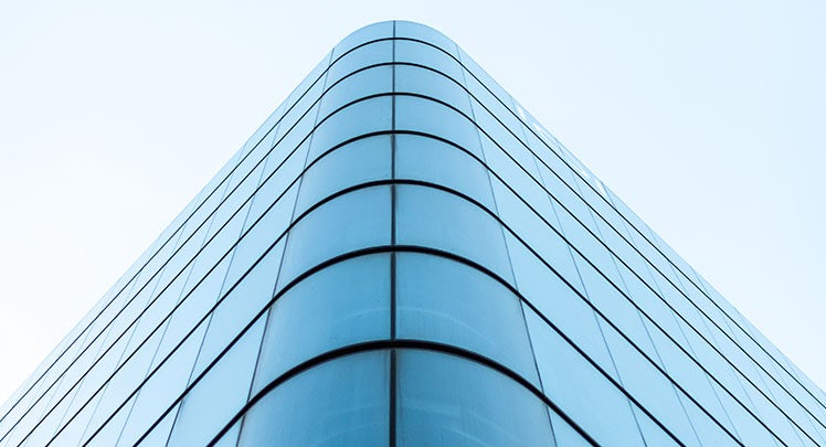 An image of a glass building with a blue sky.