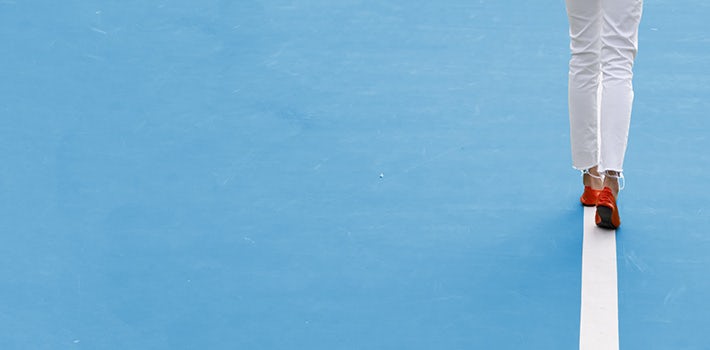 A white tennis racket on a blue wall.