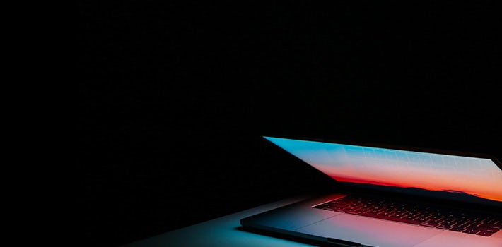 A laptop is sitting on a table in a dark room.