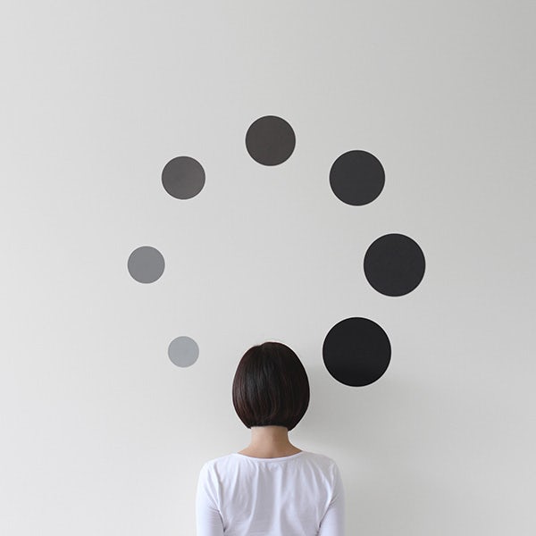 A woman looking at a wall with dots on it.