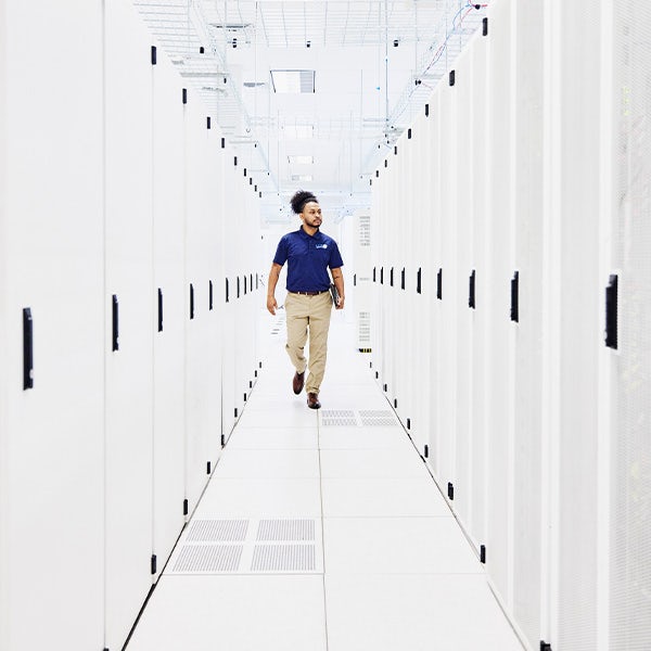 Computer engineer walking between racks of servers in data centre