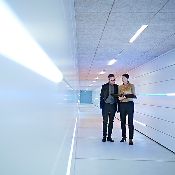 Two people standing in a hallway.