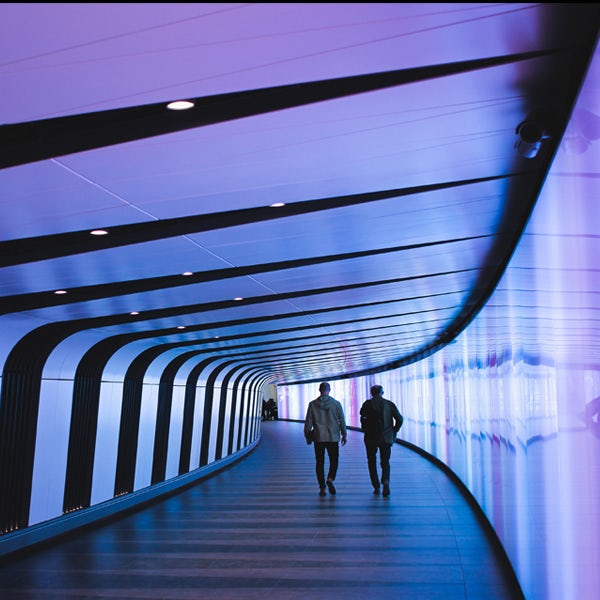 Two people walking down a tunnel.