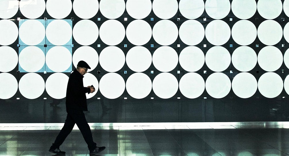 A man walking in front of a large circular wall.