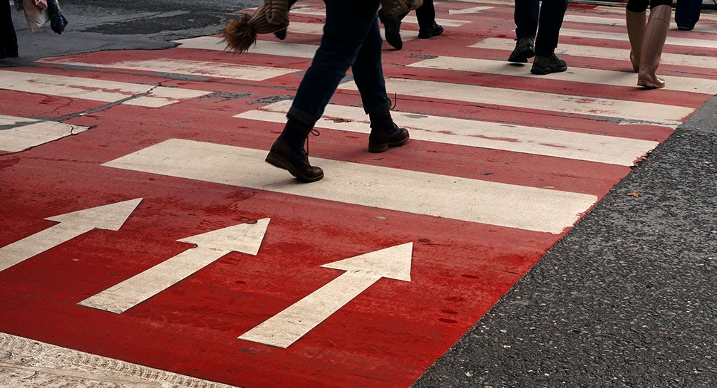 A crosswalk with arrows painted on it.