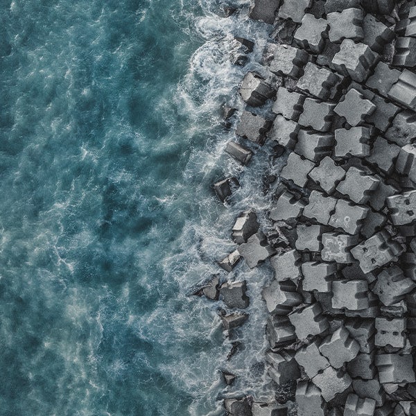 Aerial view of a large pile of bricks being hit by the sea
